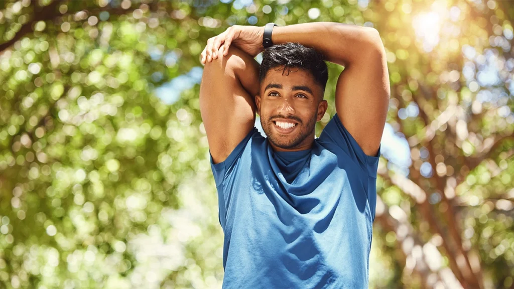Fit athletic mixed race man smiling while stretching
