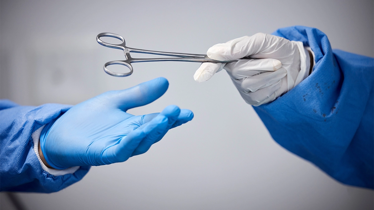 Doctor in surgery passing scissors from one hand to another