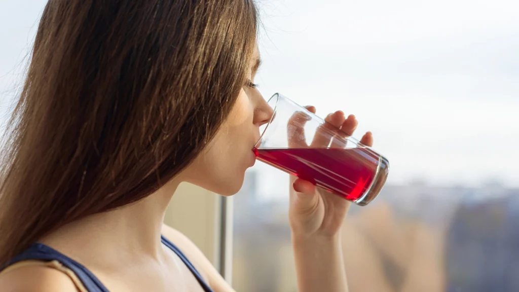 Woman drinks refreshing beverage indoors by the window